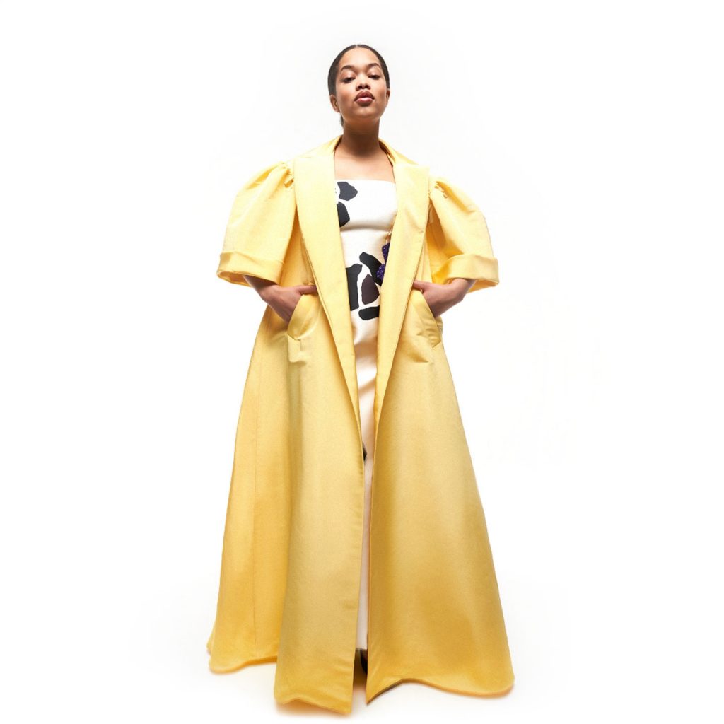 Oversized light coat with large sharp collars and a strapless corseted long print dress with high square cut slit.