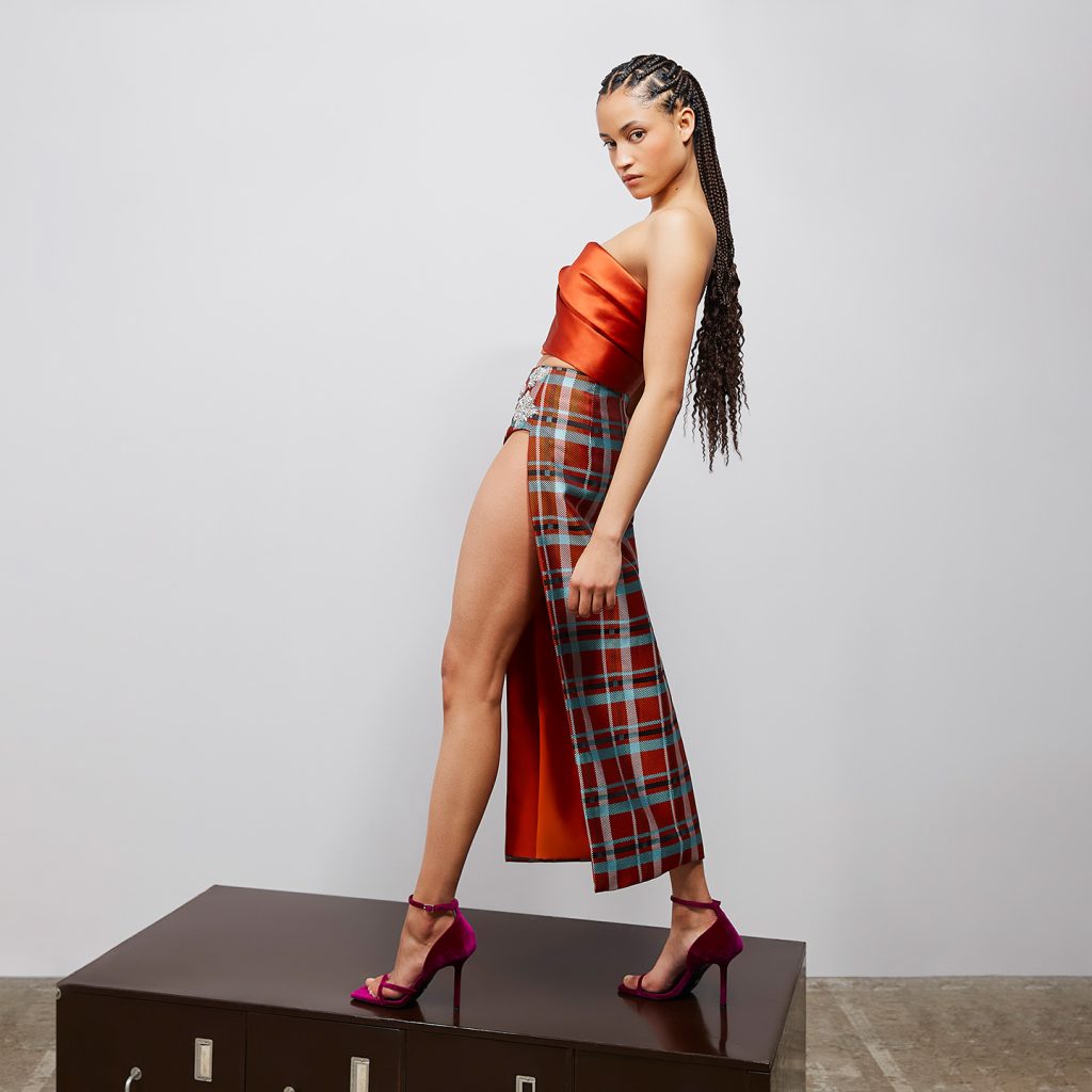 Corseted strapless top with signature bust detail, and plaid midi skirt with high slit.